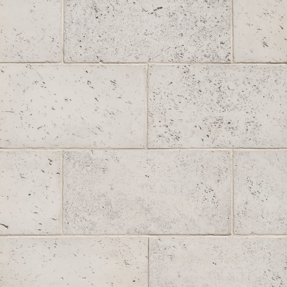 Close-up of symmetrically placed white stone veneer blocks with dark specks.