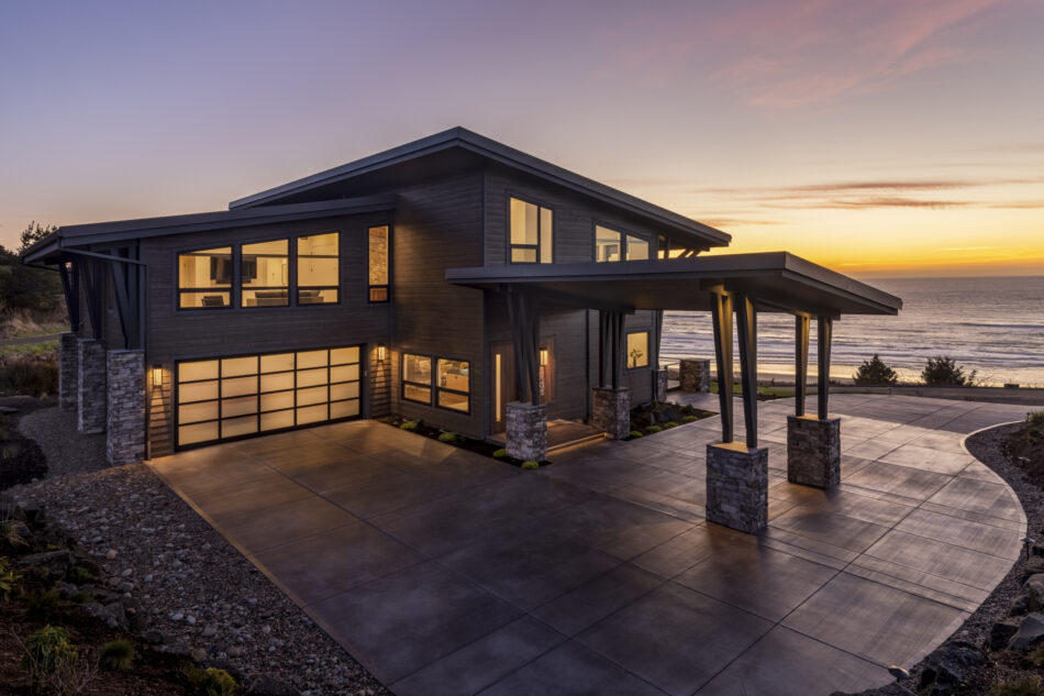 Columns of stacked stone compliment the spacious, modern driveway near a lake.