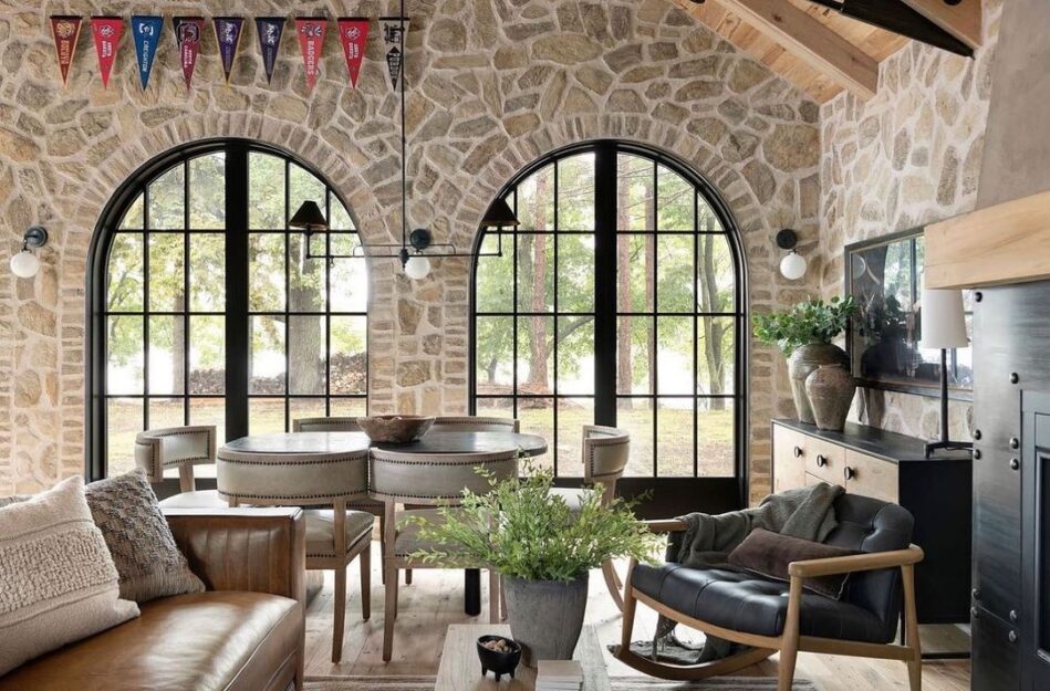 A living room featuring interior masonry veneer walls with a leather sofa, a black rocking chair and an eating area.