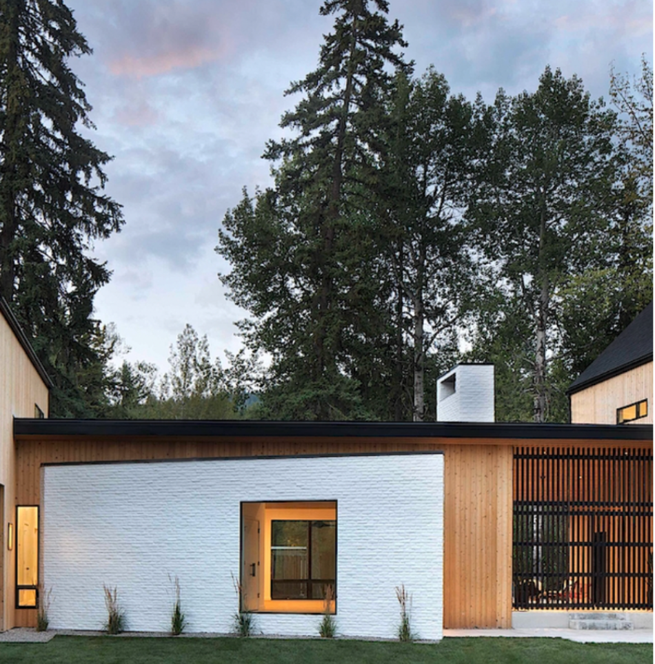 Exterior of home with vertical lap siding and a prominent white brick veneer accent wall with a window.