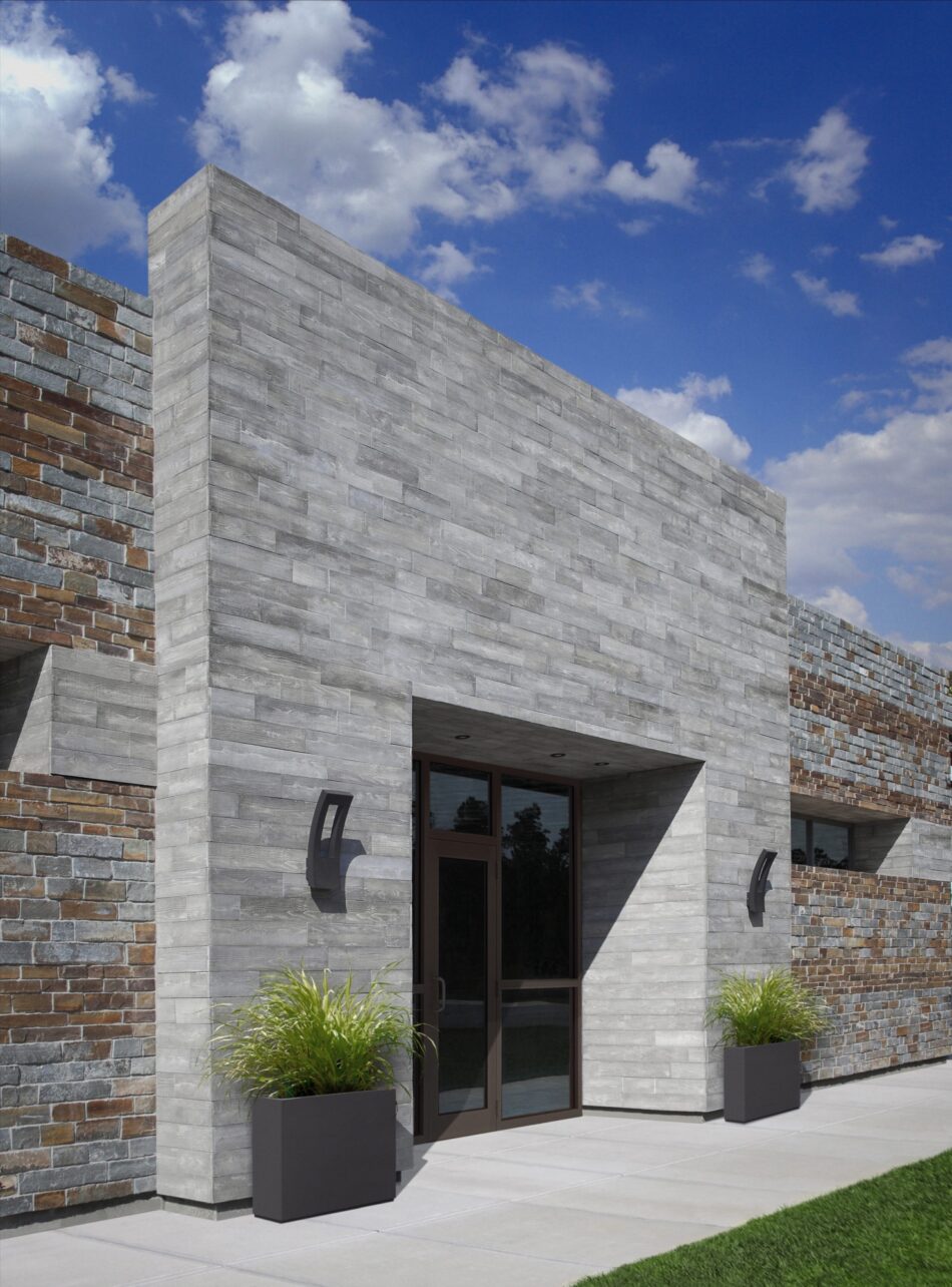 A modern brick home with a large concrete slab entryway. The entryway is made of small gray concrete blocks and has a glass door in the middle of it.