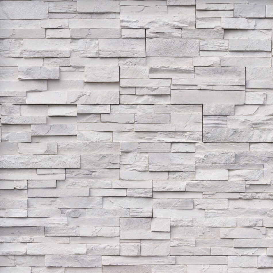 An image of a light gray, chopped stone wall. The pieces of stone are a variety of different sizes.