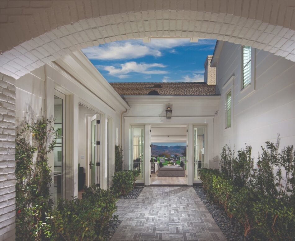 Courtyard in house with tiled floor and bushes on either side, with brick veneer archway overhead.