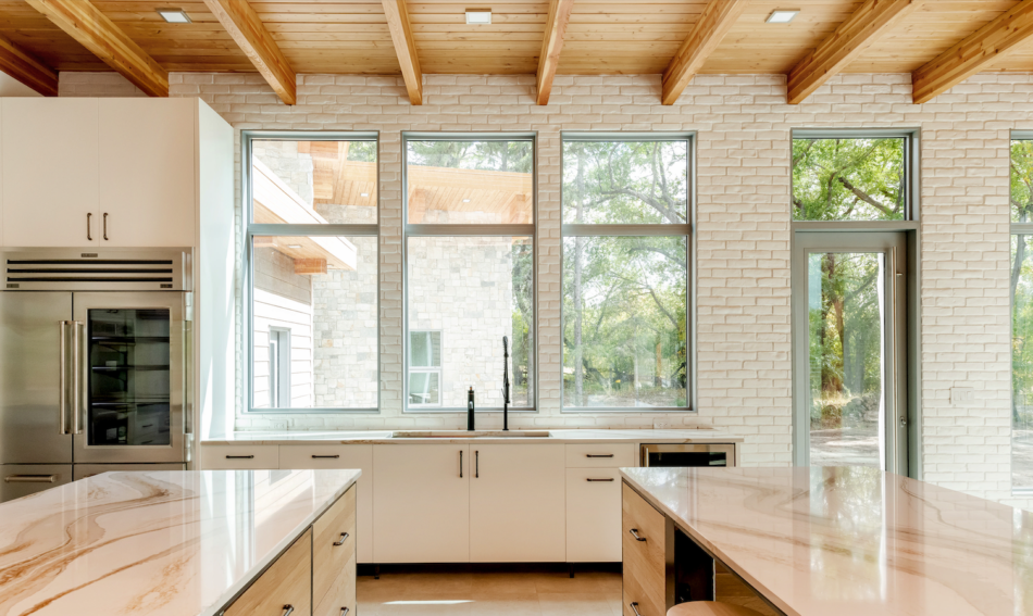 Kitchen interior with accent wall of white brick veneer studded with oversized windows.