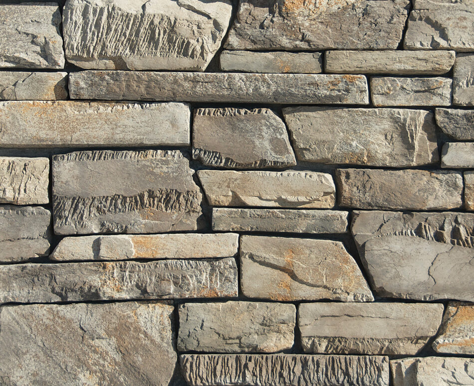 A stone veneer wall utilizing Craft Peak Ledge with rectilinear shapes and varying textures to create shadowplay, featured here in Greypearl.