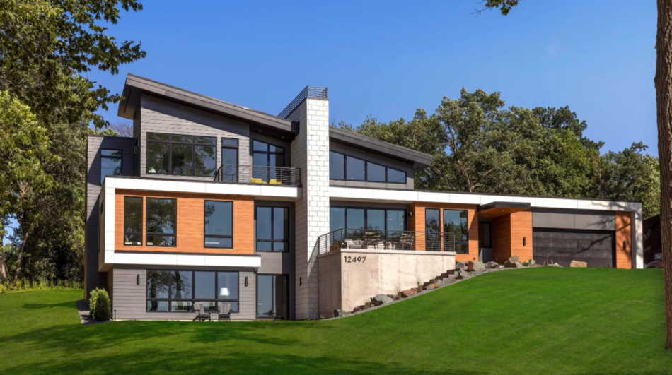 Expansive modern home featuring extensive glass, wood, concrete and limestone fireplace chimney.