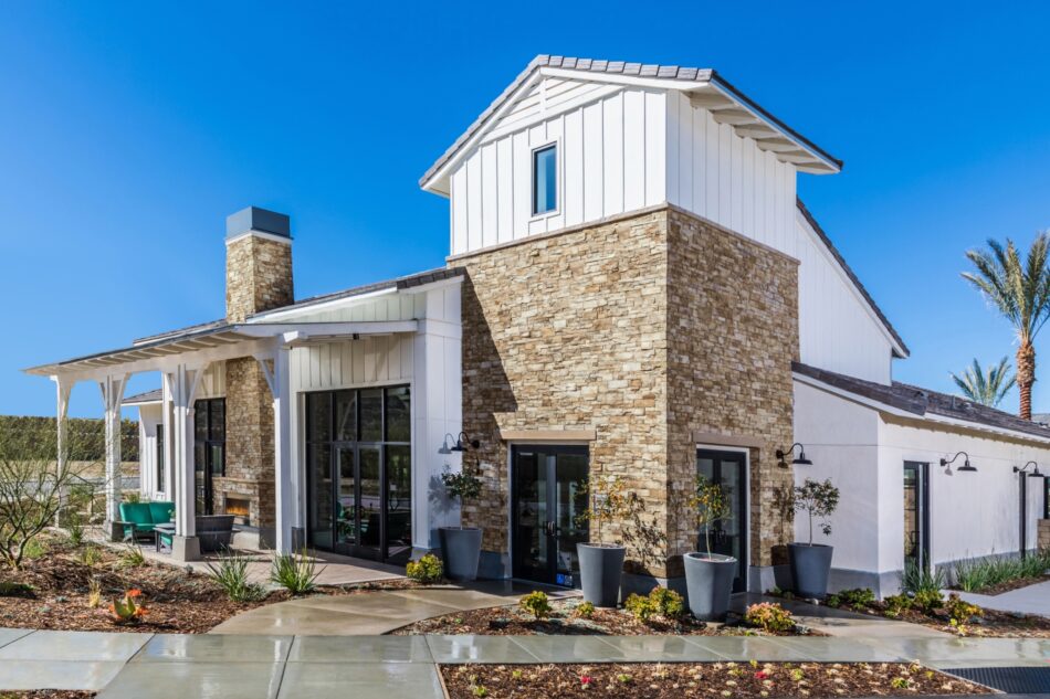 A farmhouse-style home with stone veneer siding accents. The home is white with black accents.