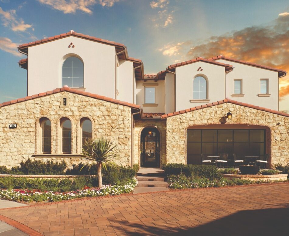 This two-story home features stone veneer on the first story. There is a beautiful sunset behind the home.