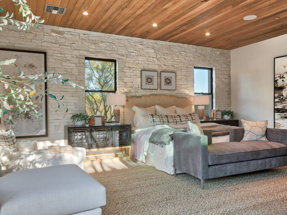 Primary bedroom with a bed and bedside tables and a large accent wall of thin stone veneer.