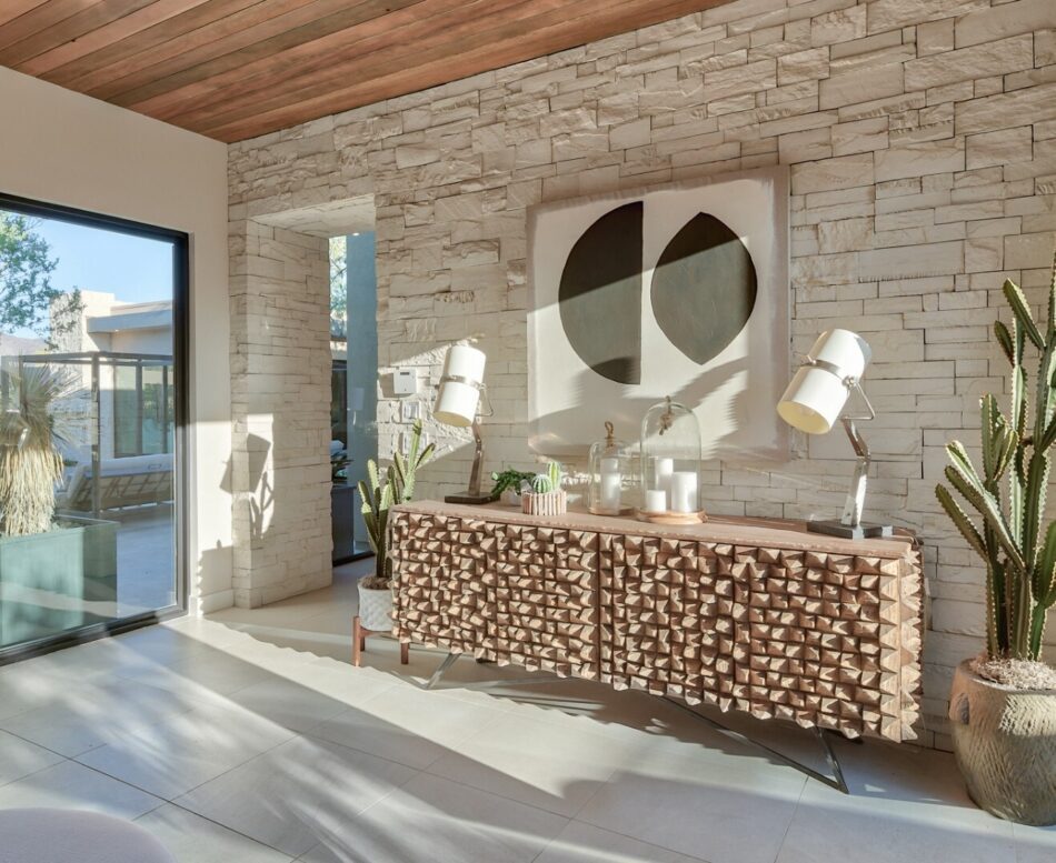 This entryway features a stone veneer accent wall. There is a painting mounted to the wall above a wooden storage cabinet.