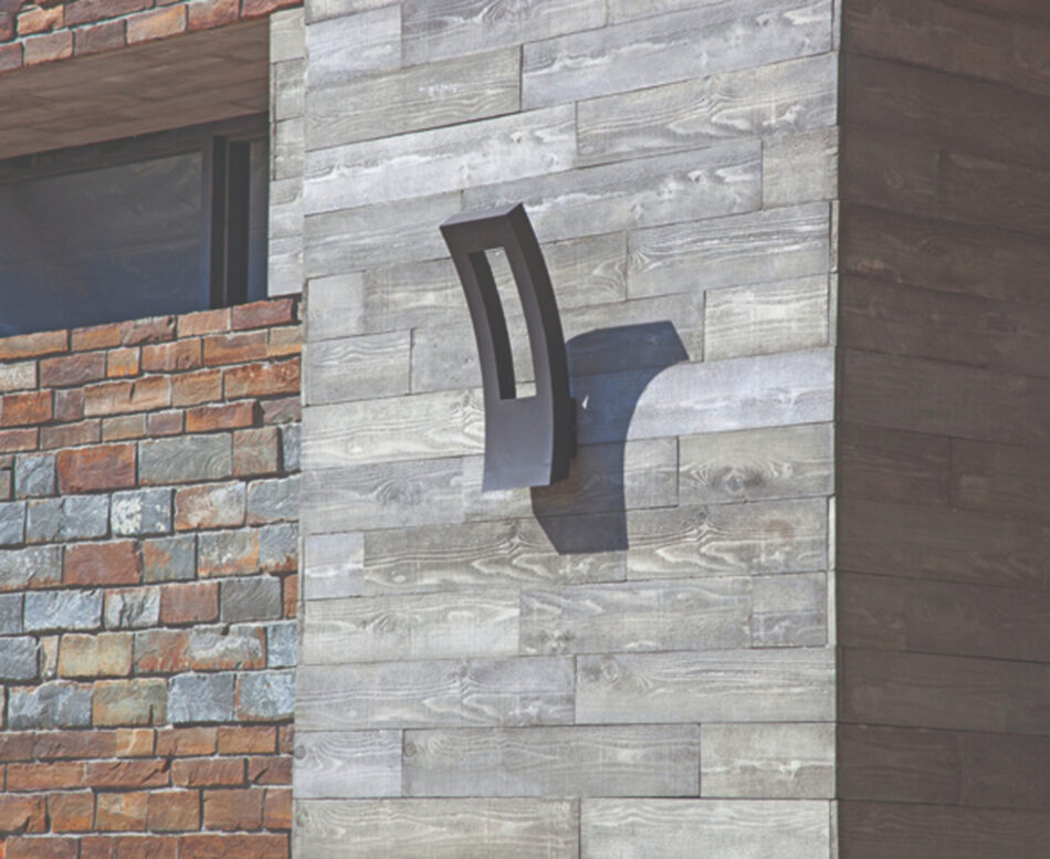 An up-close image of an exterior wood veneer wall with a mounted exterior light fixture.