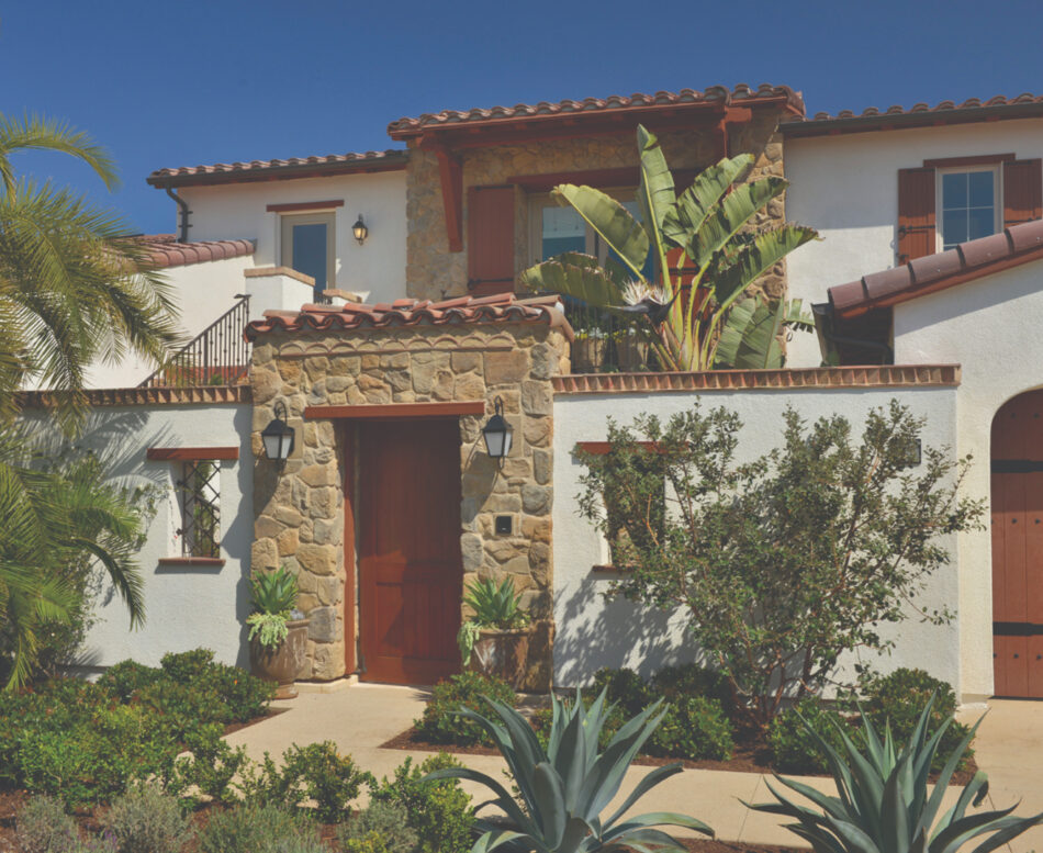 Spanish-style house with barrel tiles and white stucco and a gate made of stone.