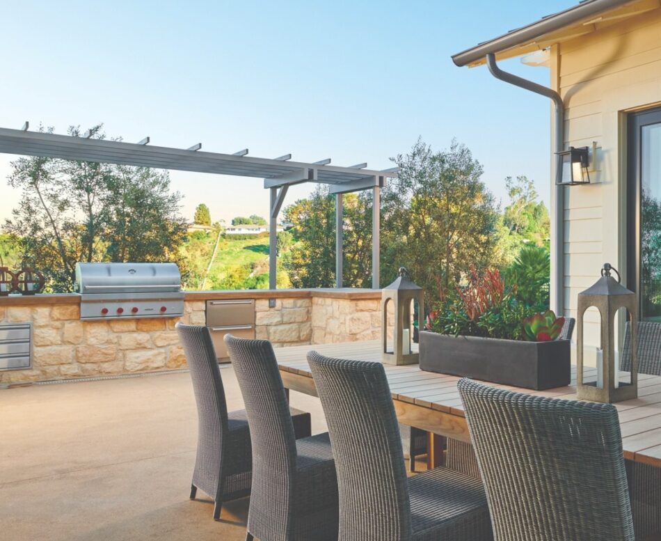 Large outdoor living space with outdoor kitchen with grill and food warmers embedded into wall of stone veneer.