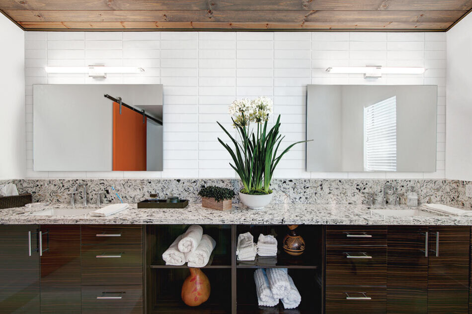 This double vanity has a marble countertop with a white brick veneer backsplash.