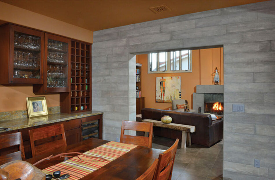 The view from inside a dining room, looking into a living room. The two areas are separated by an accent wood veneer wall.