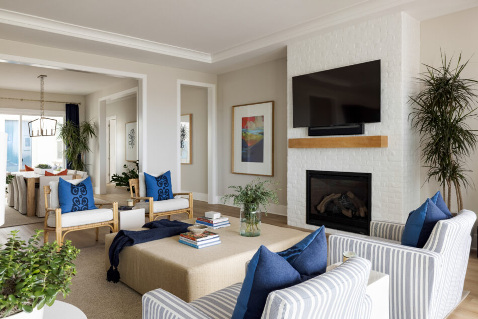 A blue and white colored living room. The room has two sets of chairs on either side of a white brick fireplace.